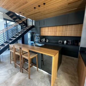 Una cocina sobria y elegante, donde la combinación de melamina negra con frentes enchapados en madera aporta carácter y calidez al espacio.