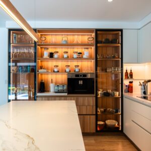 Diseño pensado para una familia que vive y trabaja desde casa. El corazón de la cocina es una coffee station enmarcada en cristal, madera e iluminación cálida, que resalta como punto de encuentro diario.