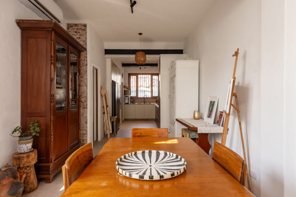 Cocina a medida en L con frentes laqueados y madera oscura.