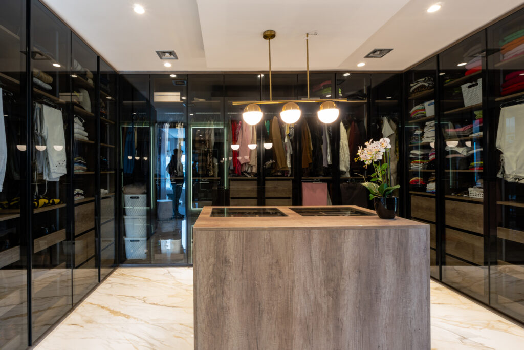 Casa Virazón I Vestidor a medida con puertas de aluminio negro y vidrio.