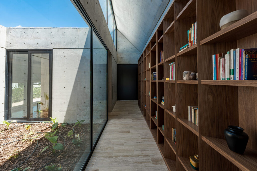 Casa Virazón II Biblioteca de ingreso en madera con estantes y módulos verticales.